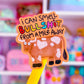 A novelty pen topper featuring a cartoon cow and the text 'i CAN SMELL BULLSHIT FROM A MILE AWAY' in colorful lettering, shown on a yellow pen against a blurred pink toy store background.